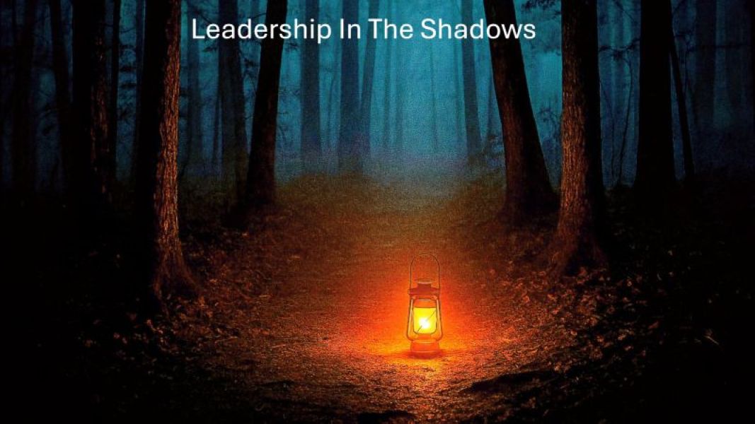 A lantern glows on a dark forest path at night, casting light among tall trees. The text Leadership In The Shadows appears at the top.